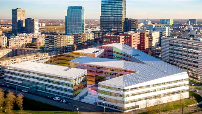 Luchtfoto van het kleurrijke en modern vormgegeven schoolgebouw van het Grafisch Lyceum Utrecht, omringd door hoge kantoorpanden en woongebouwen.